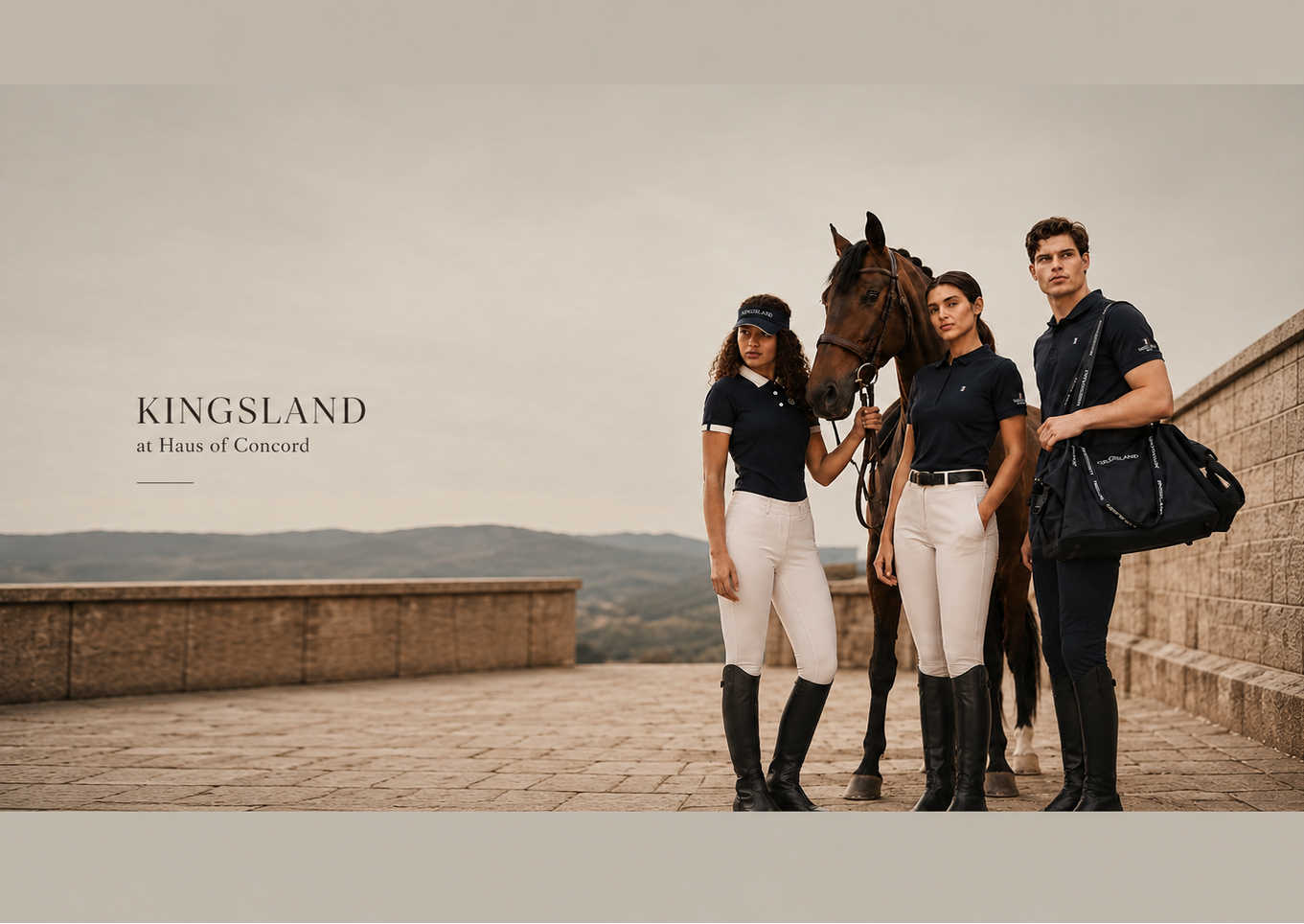 Three models in matching dark navy polo shirts and white riding breeches stand beside a horse on an outdoor stone terrace, with the text 'KINGSLAND at Home of Concour' on the left.